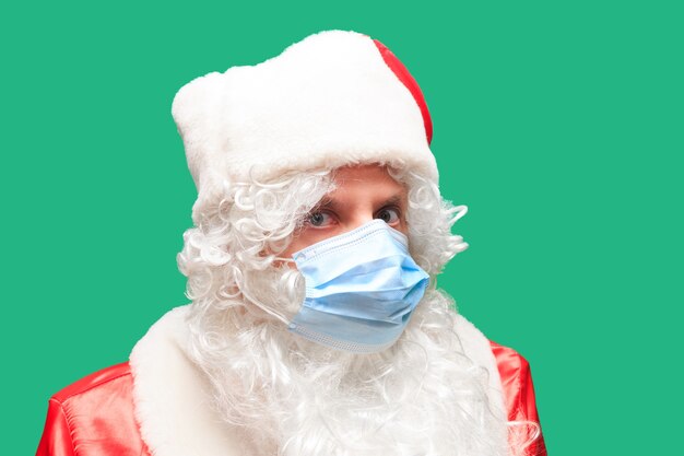 Papai noel usa uma máscara facial de papel devido a covid-19. o coronavírus é perigoso e é mundial. esteja seguro e use uma máscara. isolado. espaço para texto.