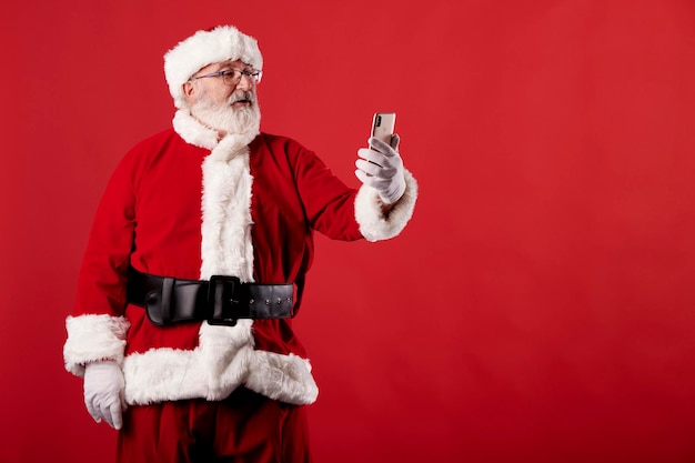 Papai Noel usando um telefone celular com fundo vermelho