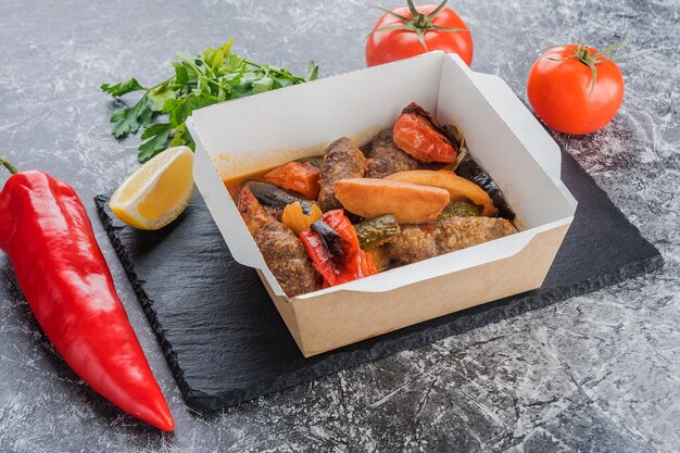 Papas al horno con salchichas y verduras en una lonchera