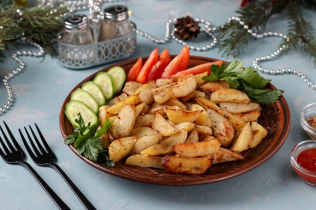 Papas al horno servidas con tomates, pepinos y perejil en un plato sobre azul claro