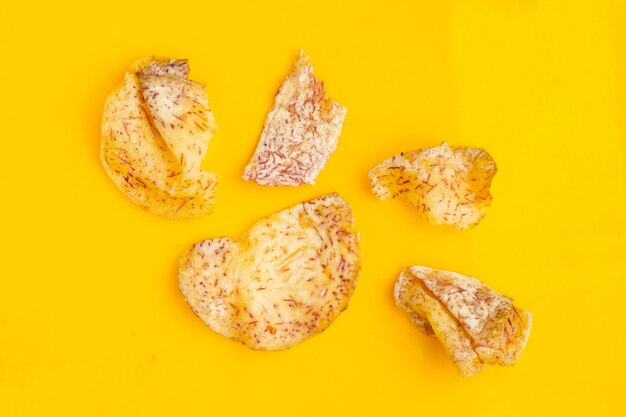 Foto papas crujientes de taro sobre un fondo amarillo