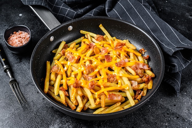 Papas fritas al horno con queso cheddar y tocino en una sartén.