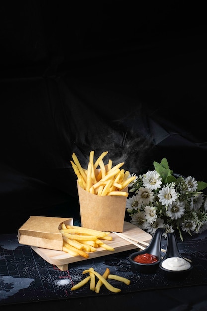 Papas fritas amarillas sobre un fondo negro con humo