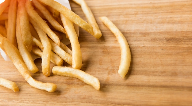 papas fritas en una bolsita de papel blanco en el tablero de madera