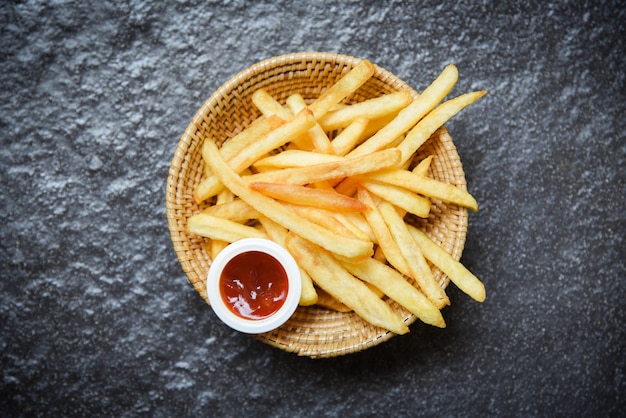 Papas fritas en canasta con salsa de tomate en la oscuridad