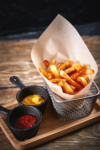 Papas fritas en canasta con salsa de tomate y salsa aislado sobre fondo negro