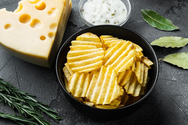 Papas fritas caseras con queso y cebolla, con salsas, sobre fondo de piedra gris