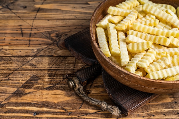 Papas fritas congeladas del horno de la arruga se pega en una placa de madera.