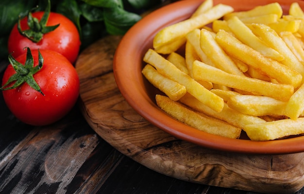 Papas fritas frescas y sabrosas y salsa roja en una tabla de cortar de madera