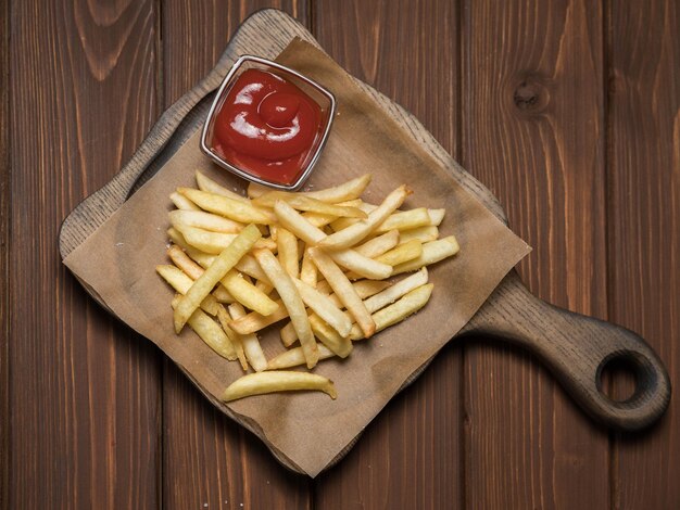 Papas fritas con ketchup en un servidor de madera y fondo de madera Alimentos poco saludables Colesterol