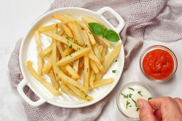 papas fritas con mayonesa y salsa picante sobre fondo blanco