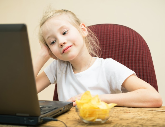 Papas fritas y una niña delante de un ordenador portátil.