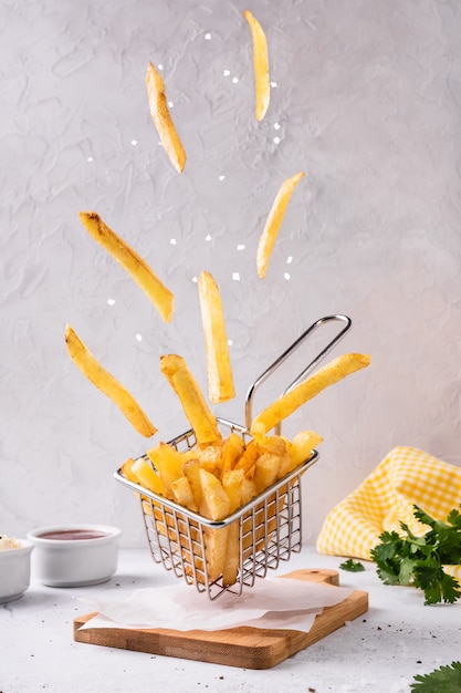 Foto papas fritas patata con sal volando en la cesta.