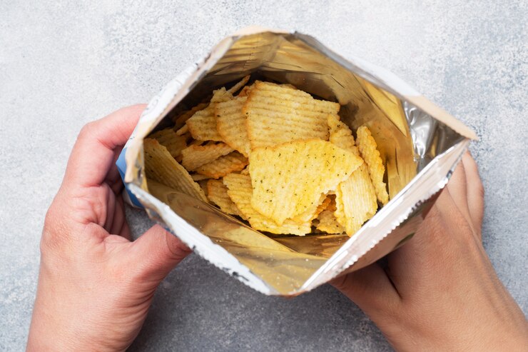 Las papas fritas con picante en un paquete abierto se dan la mano. Cerrar enfoque selectivo.