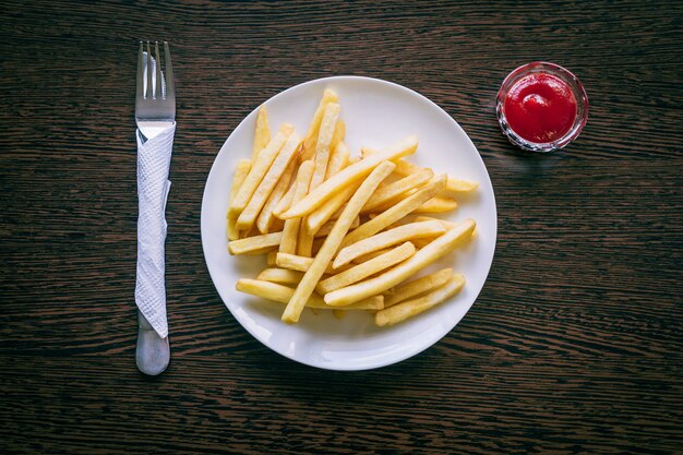 Papas fritas en un plato blanco con salsa de tomate