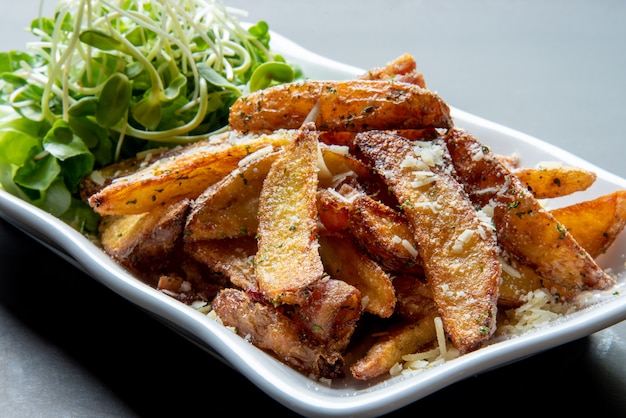 Papas fritas en un plato blanco con vegetales