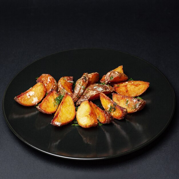 papas fritas en un plato negro sobre un fondo negro