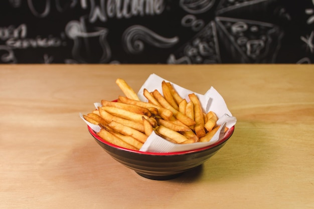 Papas fritas en un plato pequeño sobre una mesa de madera.