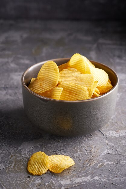 Papas fritas en un recipiente gris sobre un fondo gris