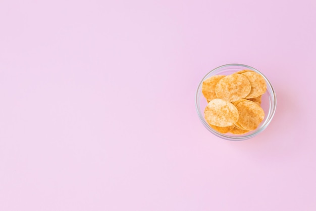 Papas fritas en recipiente de vidrio sobre fondo rosa Comida rápida