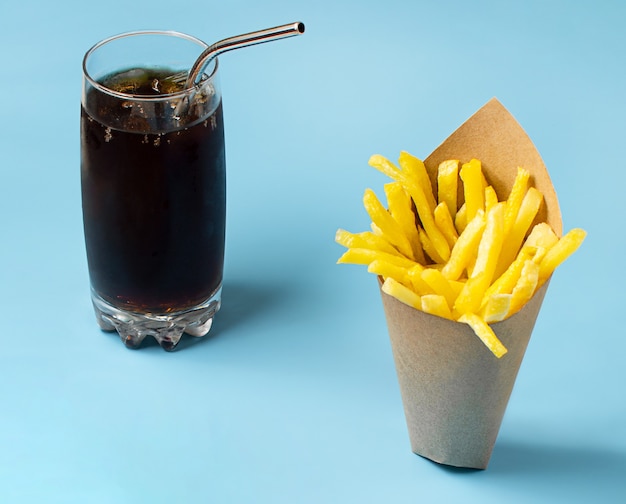 Papas fritas y refrescos sobre fondo azul.