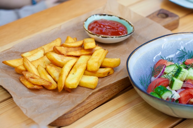 Papas fritas con salsa de tomate y ensalada de verduras en el restaurante