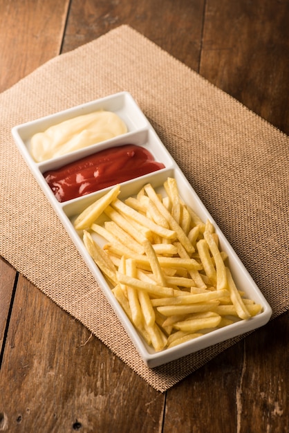 Papas fritas con salsa de tomate en el fondo de madera.