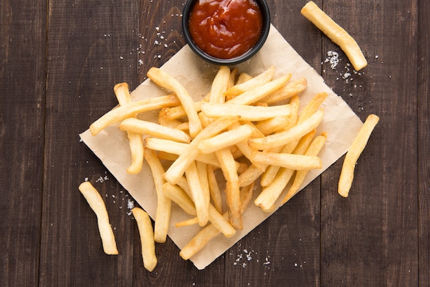 Papas fritas con salsa de tomate en la mesa de madera.