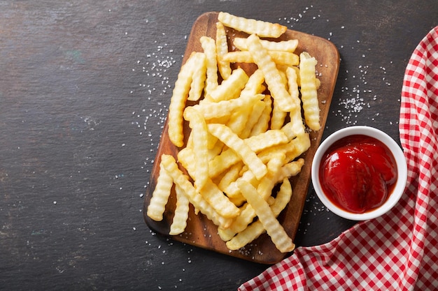 Papas fritas con salsa de tomate en mesa oscura