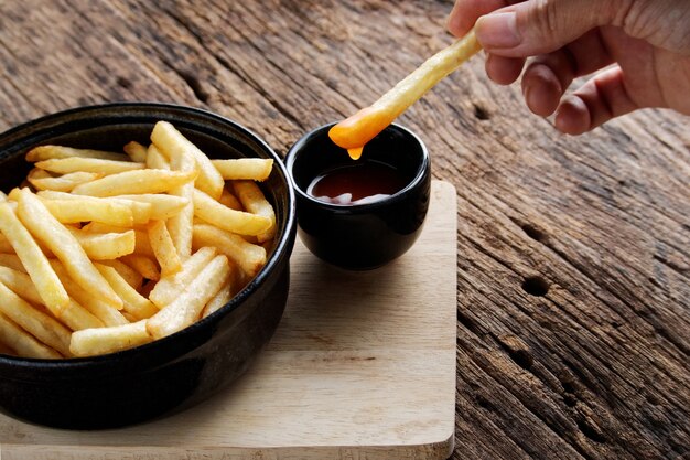 Papas fritas con salsa de tomate sobre un fondo de madera oscura. bocadillo de comida rápida.