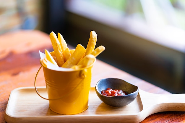 Papas fritas y salsa de tomate sobre tabla de madera