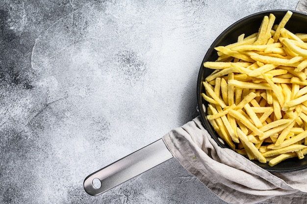 Papas fritas en una sartén. Fondo gris Vista superior. Espacio para texto