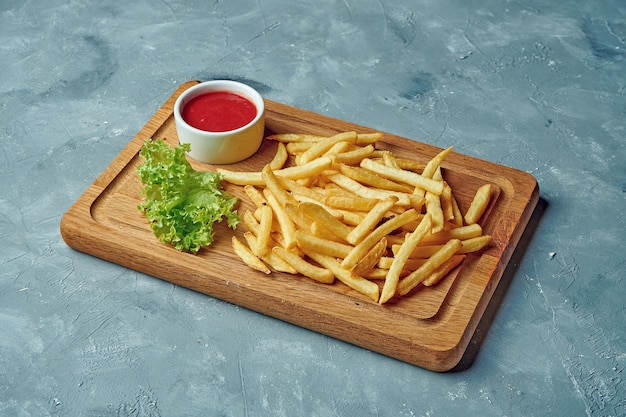 Papas fritas en tablero de madera con salsa