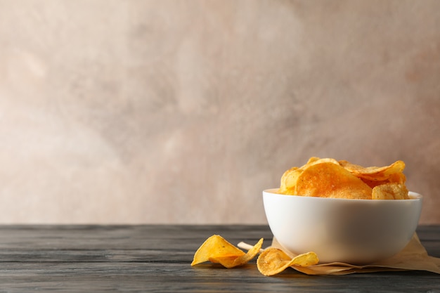 Papas fritas en un tazón, papel artesanal en mesa de madera en marrón, espacio para texto