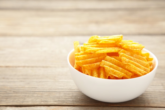 Papas fritas en un tazón en la pared de madera gris