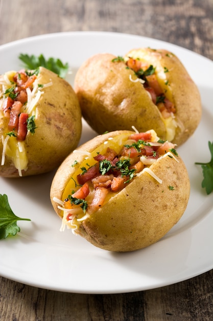 Papas rellenas con tocino y queso en el plato en la mesa de madera