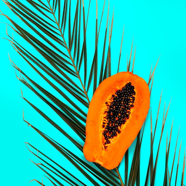 Papaya auf blauem Hintergrund. Flache minimale vegane Kunst