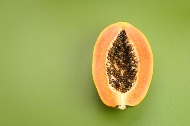 Papaya cortada por la mitad sobre fondo verde, espacio para texto