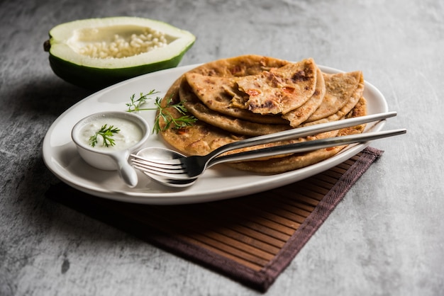 Foto papaya cruda paratha o papita ke parathe elaborado con papaya, harina de trigo, semillas de comino y jengibre. receta popular de comida india servida caliente con cuajada. enfoque selectivo