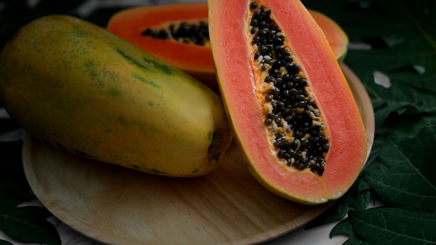 papaya dulce entera ya la mitad en placa de madera