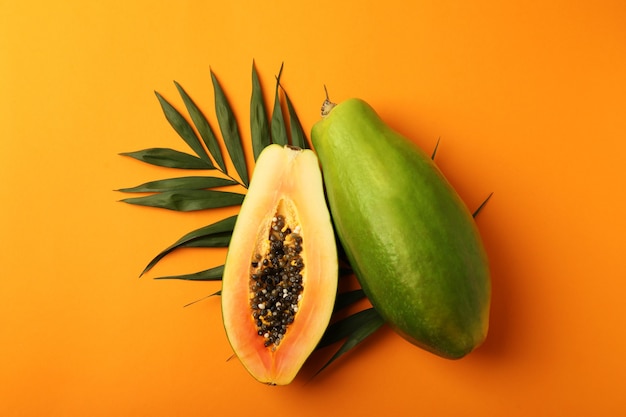 Papaya madura con hojas sobre fondo naranja