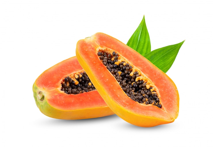 Foto papaya rebanada madura con hojas en la pared blanca.