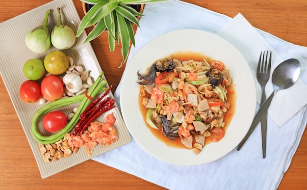 Papaya-Salat (Som Tam) die traditionellen thailändischen Speisen auf Holztischhintergrund.