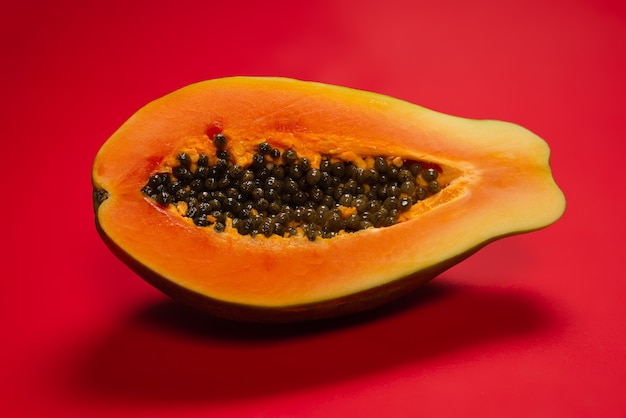 Papayafrucht auf einem orangefarbenen Hintergrund. Tropische Frucht. Halbe Papaya.