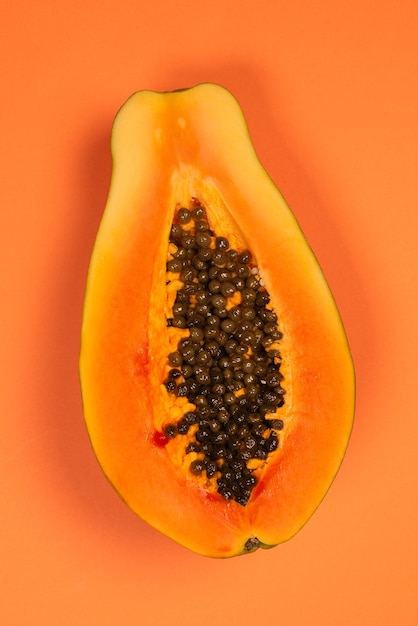 Papayafrucht auf einem orangefarbenen Hintergrund. Tropische Frucht. Halbe Papaya.