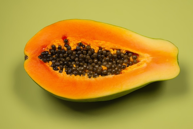 Papayafrucht auf grünem Hintergrund. Tropische Frucht. Halbe Papaya.