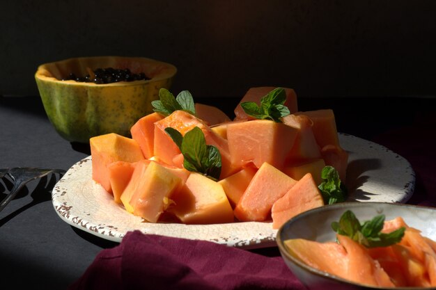 Papayafrucht auf weißem Teller auf dunklem Hintergrund