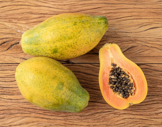 Papayas mit halber Frucht über Holztisch