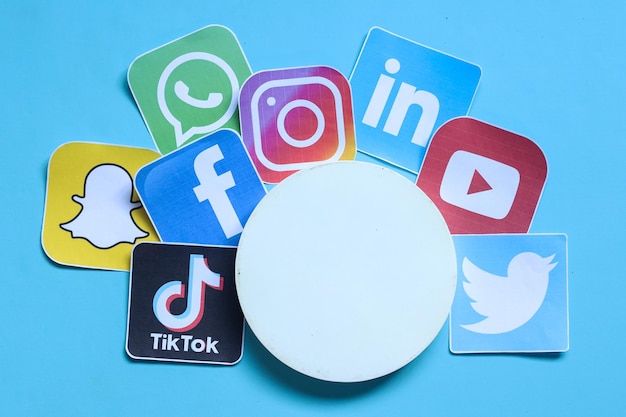 Foto papéis impressos do logotipo de aplicativos de mídia social com pódio circulado branco isolado sobre fundo azul