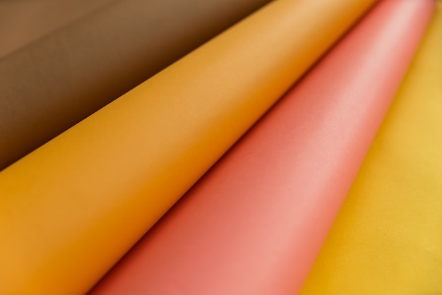 Papéis rosa, marrons e laranja, dobrando-se sobre o papel de cor amarela em forma abstrata. Fundo de papel de cor abstrata.